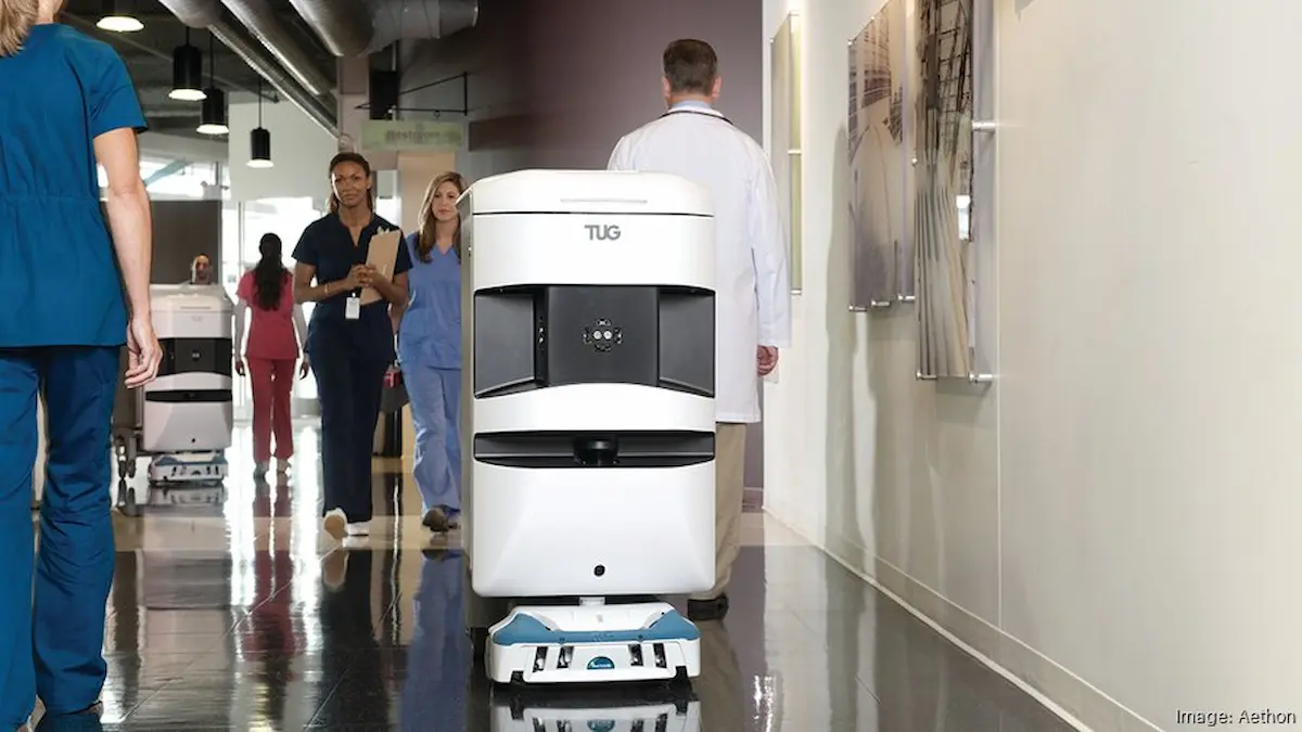 Robot vận chuyển y tế Aethon TUG tương tác nhân viên y tế trong hành lang.